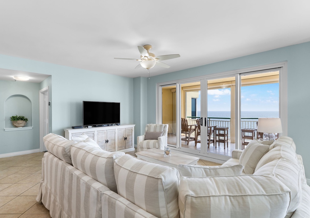 Beach Colony Tower 10C- Step into your coastal retreat where soft blue hues meet plush seating, perfectly arranged to frame breathtaking ocean views beyond your private balcony. The sea awaits just beyond the glass.