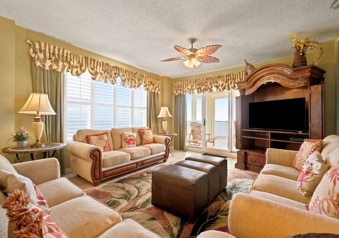 Beach Colony W13A- Relax in your spacious living room with plush seating, coastal décor, and a balcony door opening to ocean views—perfect for unwinding after a day at the beach.