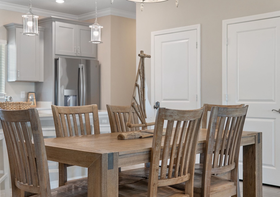 Saltwater & Sunsets- Gather around this spacious dining table—perfect for family meals and shared stories. Natural wood warmth meets coastal charm, with the open kitchen just steps away for easy entertaining.