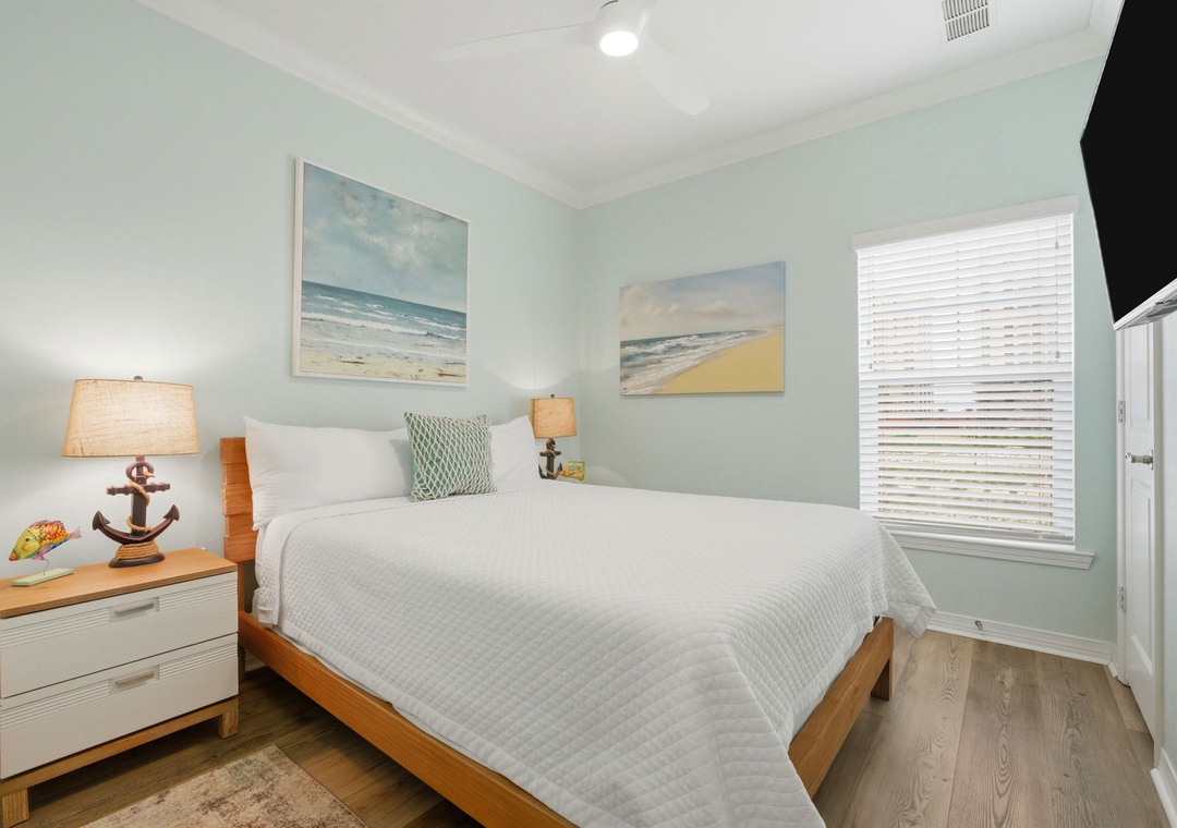 Drift off in your serene coastal retreat with soft blue walls, beach-themed artwork, and cozy textured bedding that invite peaceful dreams by the shore.