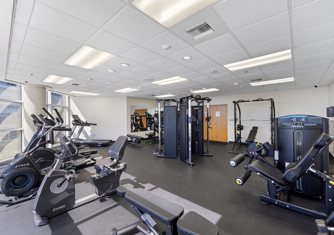 Stay on track with your fitness goals in this well-equipped gym featuring cardio machines, free weights, and strength training equipment—all bathed in natural light.