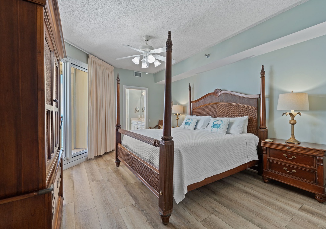 Beach Colony T15B- Sink into coastal comfort in your elegant bedroom, where soothing seafoam walls and a stately four-poster bed welcome you after a day at the beach. Your private balcony awaits just beyond those sliding doors.