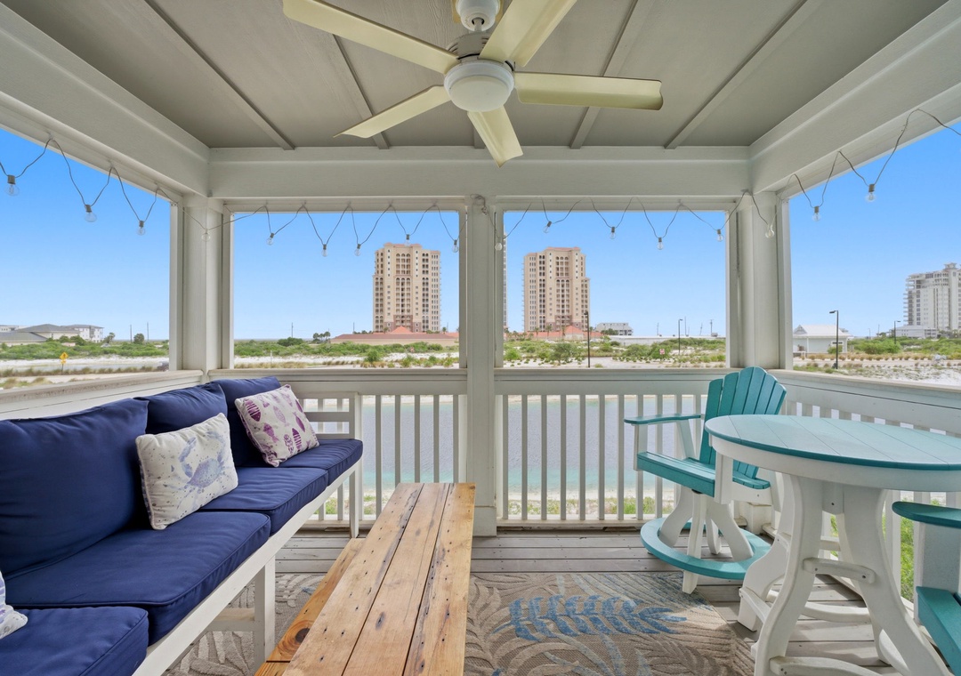 The screened porch offers distant coastal views across the surrounding area, with a ceiling fan and comfortable seating for outdoor relaxation.