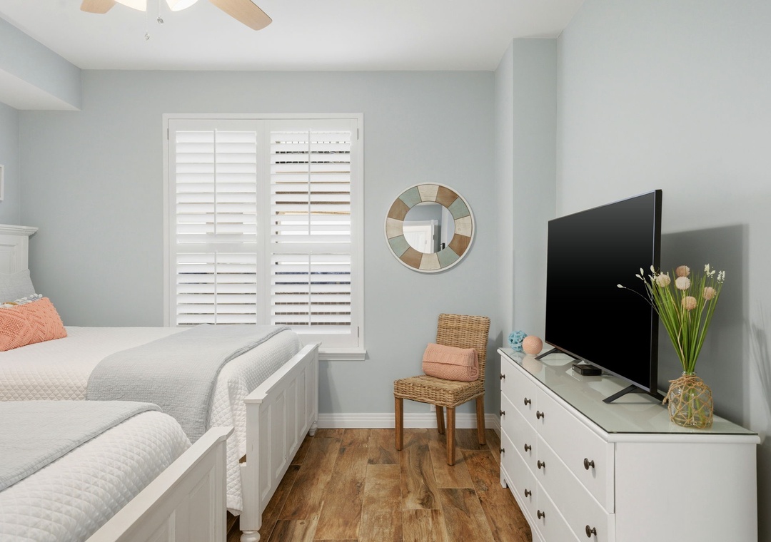 Beach Colony Tower PH1B -Rest easy in your serene coastal-inspired bedroom, where soft blue walls and natural light create a calming retreat. Enjoy your favorite shows on the flat-screen TV, unwind with a book in the cozy wicker chair