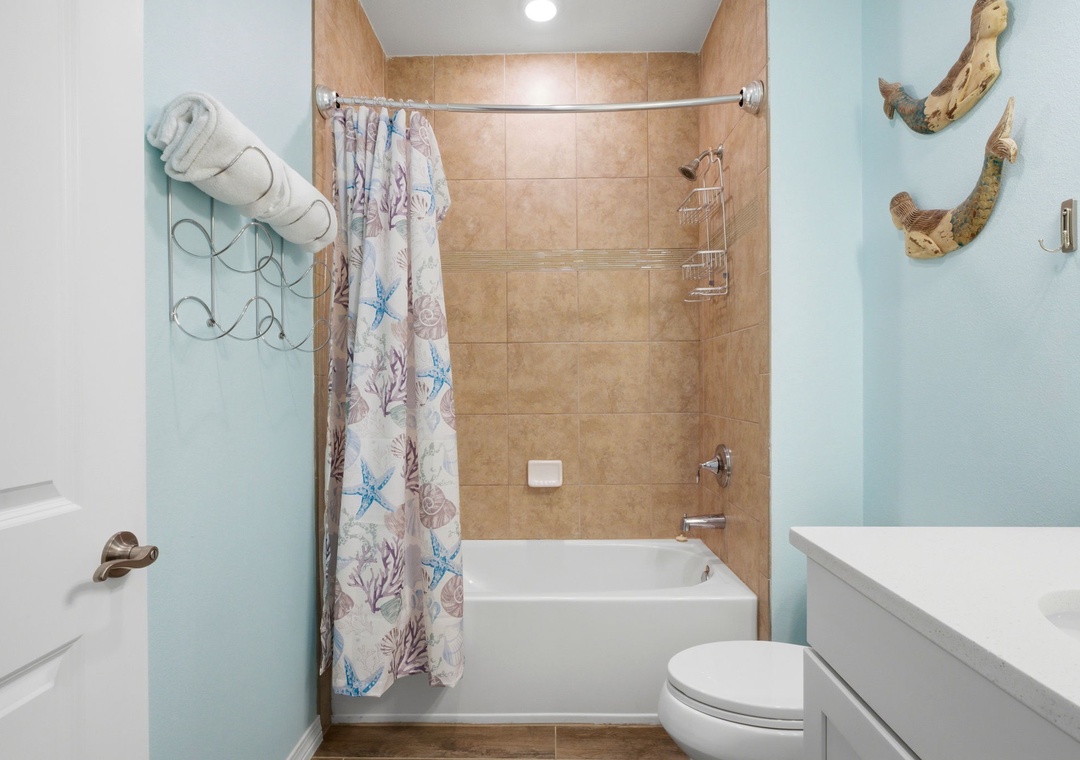Your coastal-inspired bathroom features a relaxing tub and shower combo, complemented by soothing ocean hues and charming seaside decor that invites you to unwind after your beach adventures.