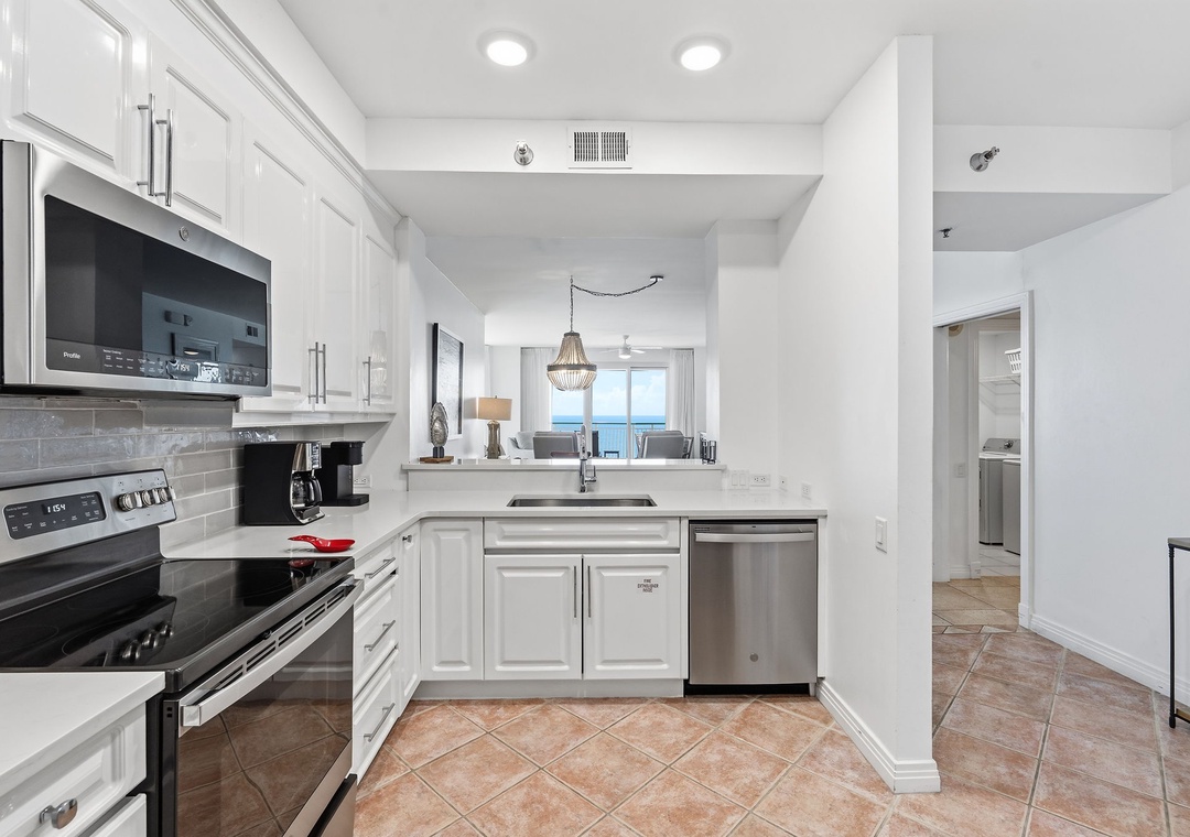 Beach Colony T14B- Gather in this bright, modern kitchen with sleek white cabinetry and stainless-steel appliances, perfect for preparing your favorite meals. Through the open layout, you'll glimpse beautiful Gulf views.