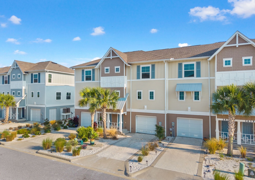 Saltwater & Sunsets- Coastal townhomes with tropical landscaping and beach-style architecture in a relaxed neighborhood setting, showcasing the property's charming exterior and sandy front yards.