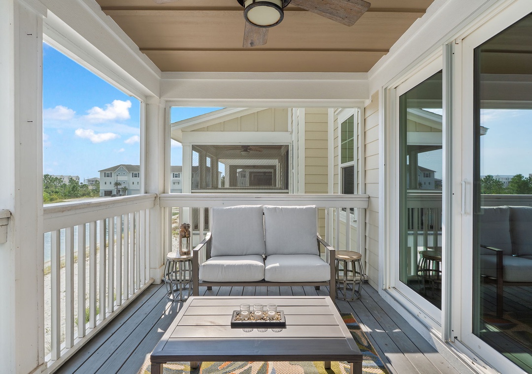 Saltwater & Sunsets- Step out onto your private covered balcony where coastal breezes meet comfort. Settle into the loveseat with a morning coffee and take in the neighborhood views framed by classic railings and warm wood accents above.
