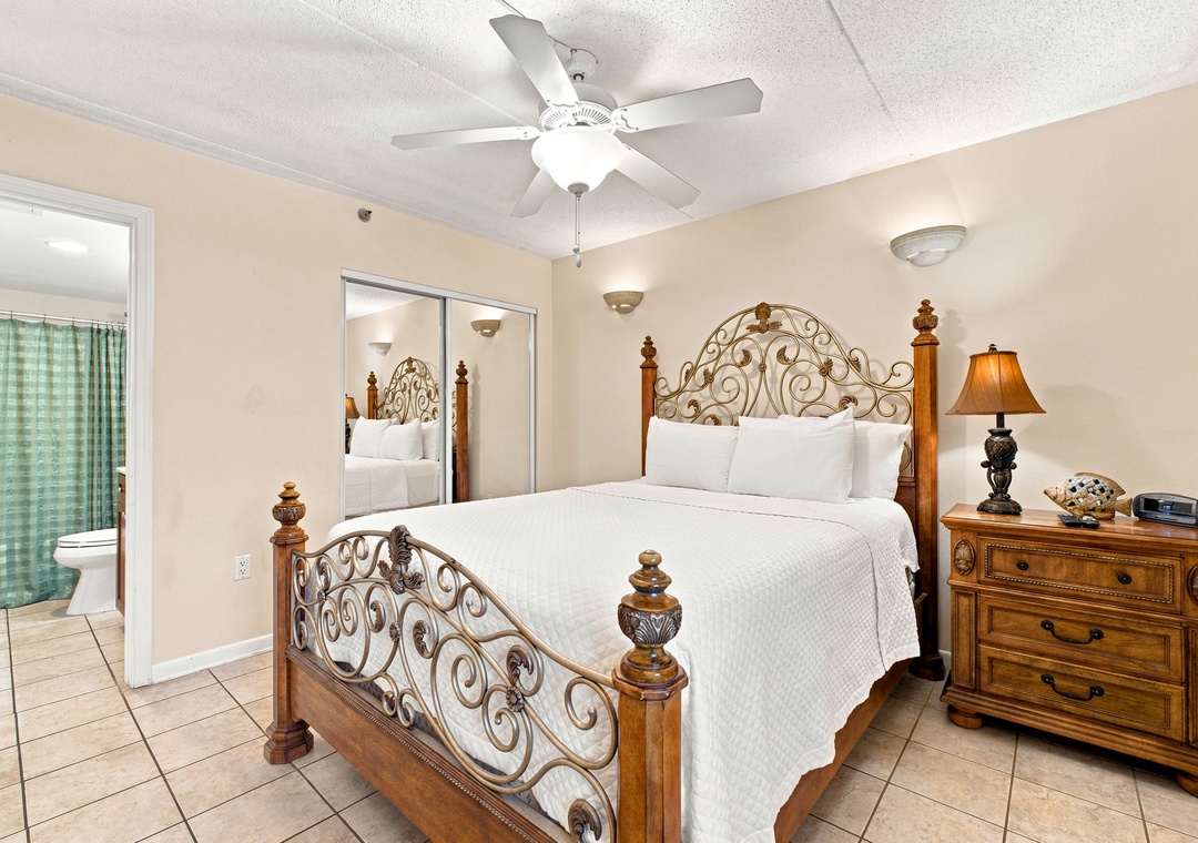 Ocean Breeze W 105- Your restful bedroom features an ornate bed with crisp linens, a ceiling fan for comfort, and warm lighting that creates a peaceful retreat.