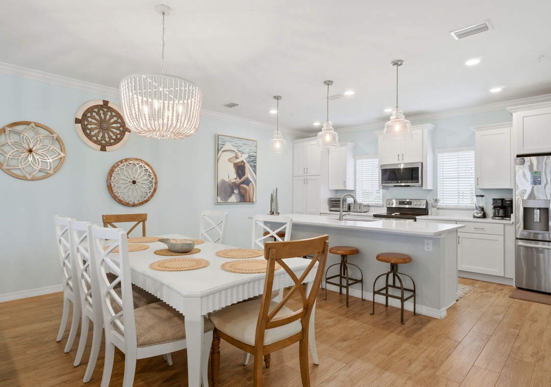 Step into your bright, coastal-inspired kitchen and dining area where you'll love preparing meals at the spacious island or gathering around the table with loved ones under the soft glow of the chandelier.