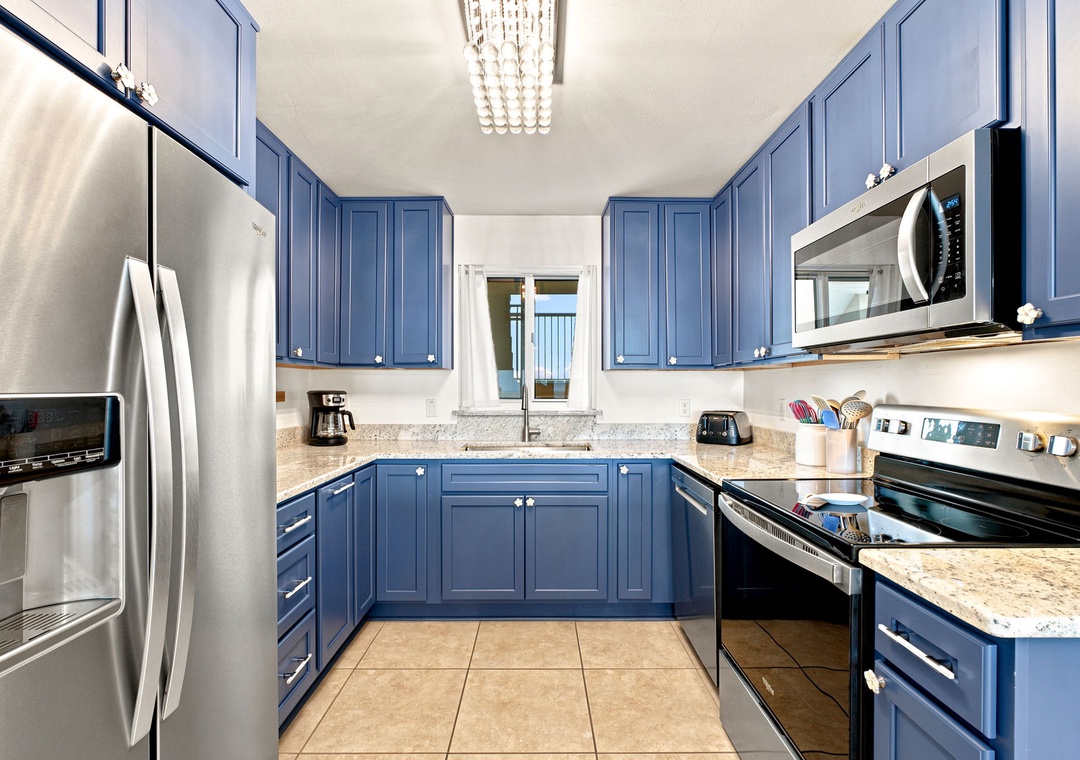 Sandy Key 411- Your fully equipped kitchen features stylish blue cabinetry, granite countertops, and stainless steel appliances—perfect for preparing meals at your own pace during your stay.