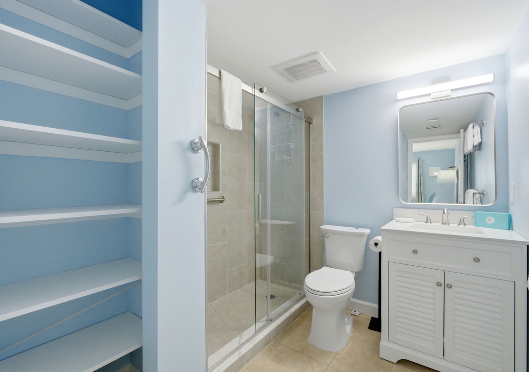 Sandy Key 637- Refresh in your private bathroom with soft blue tones, modern fixtures, and a glass-enclosed shower. Storage shelves keep your essentials organized.