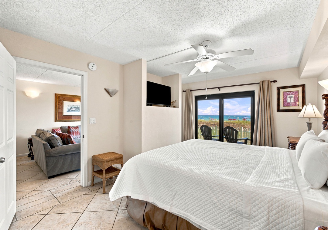Ocean Breeze W 105- Step into your peaceful retreat with plush bedding and an ocean view framed perfectly through your glass doors. Cool tile floors and a ceiling fan keep you comfortable, while the beach beckons just beyond.
