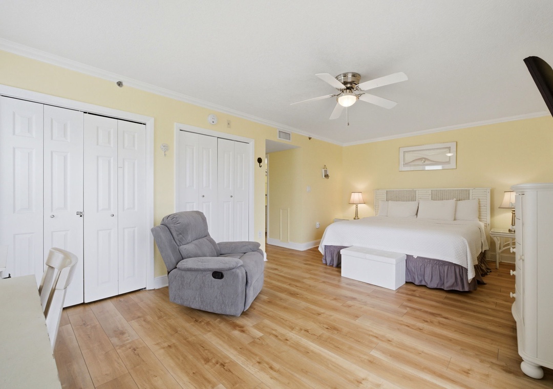 Ocean Breeze E601- Unwind in your spacious bedroom with warm coastal tones, plush king bed, and a cozy recliner—perfect for relaxation after exploring the area.