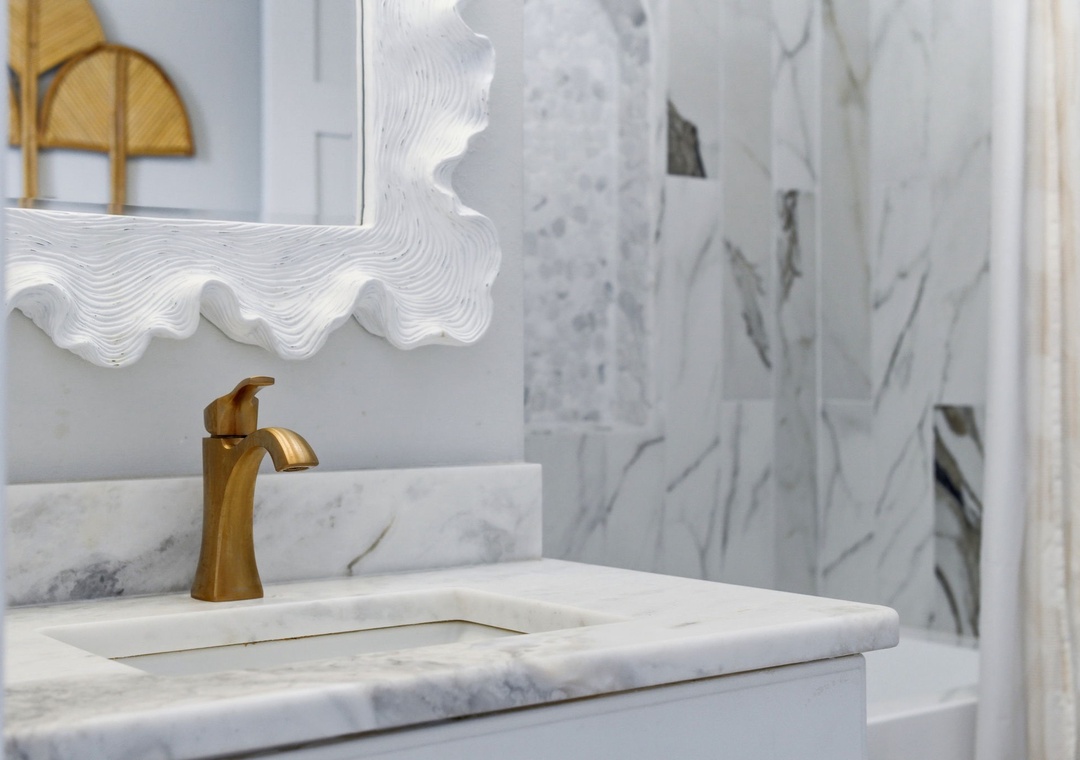 North Lost Key Landing B2- Elegant marble vanity with brass fixtures and a unique wave-detailed mirror creates a spa-like retreat where you can start each day feeling refreshed.