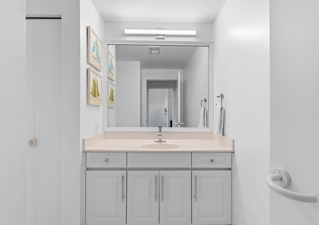 Beach Colony T14B- Step into your beautifully appointed bathroom with soft white vanity, calming coastal artwork, and fresh towels waiting just for you.