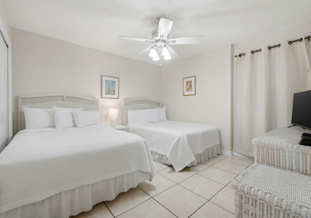 Ocean Breeze E702- Drift off in your bright, breezy bedroom with two plush beds dressed in crisp white linens. A ceiling fan keeps you cool, coastal artwork sets the mood, and a flatscreen adds modern comfort to your peaceful retreat.