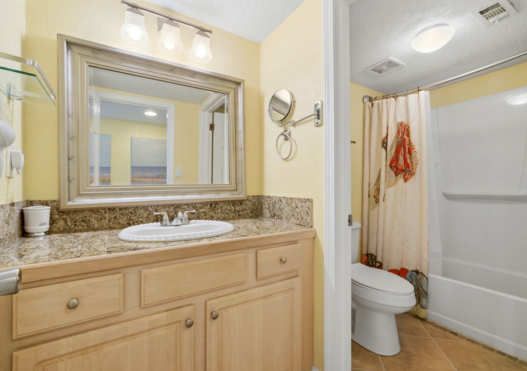Ocean Breeze E601- Bathroom offers a granite-topped vanity, bright lighting, and a full tub-shower combo—perfect for unwinding after a day at the beach.