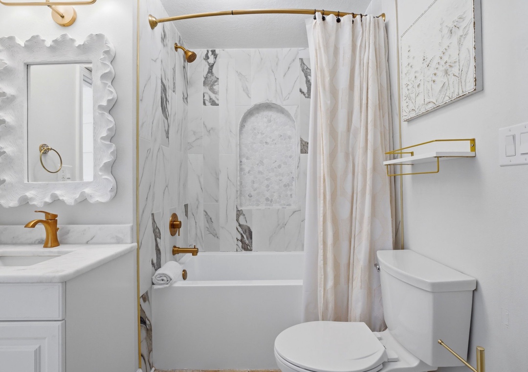 North Lost Key Landing B2- Beautifully updated bathroom featuring elegant marble-look tile, a tub/shower combo, and chic gold fixtures—your own bright, stylish retreat after a day exploring.