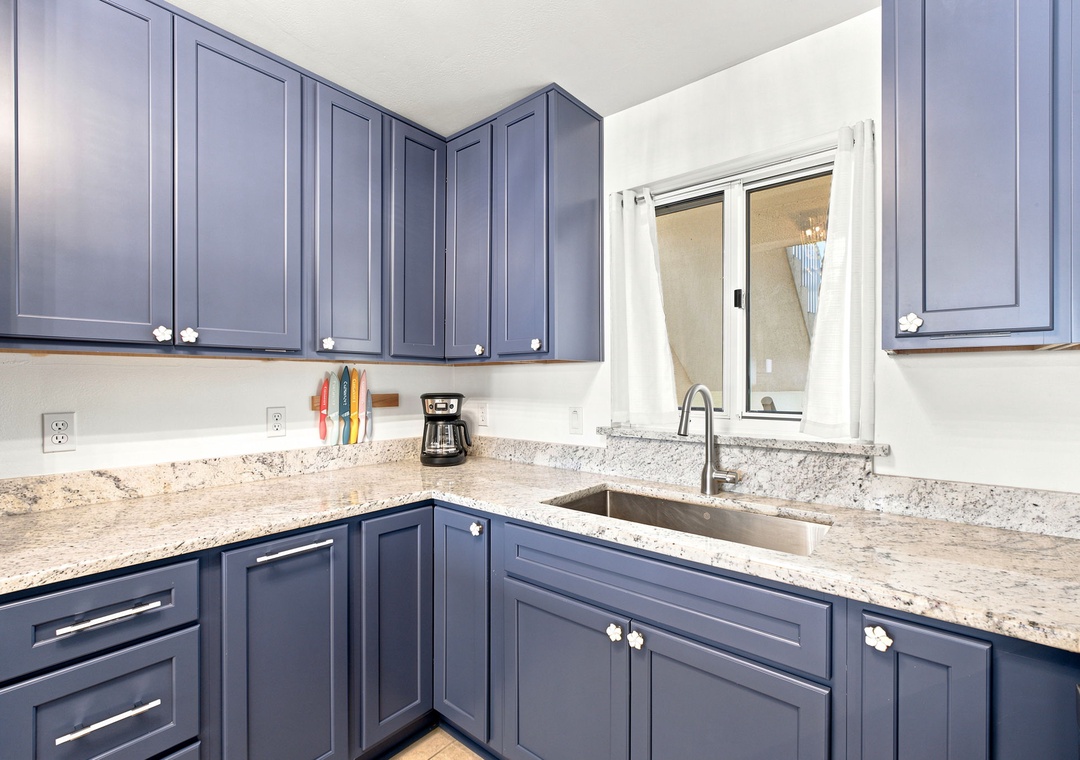 Sandy Key 411- Your kitchen blends modern style with practical comfort—sleek blue-gray cabinetry, elegant granite counters, and a bright window that invites natural light into your cooking space.