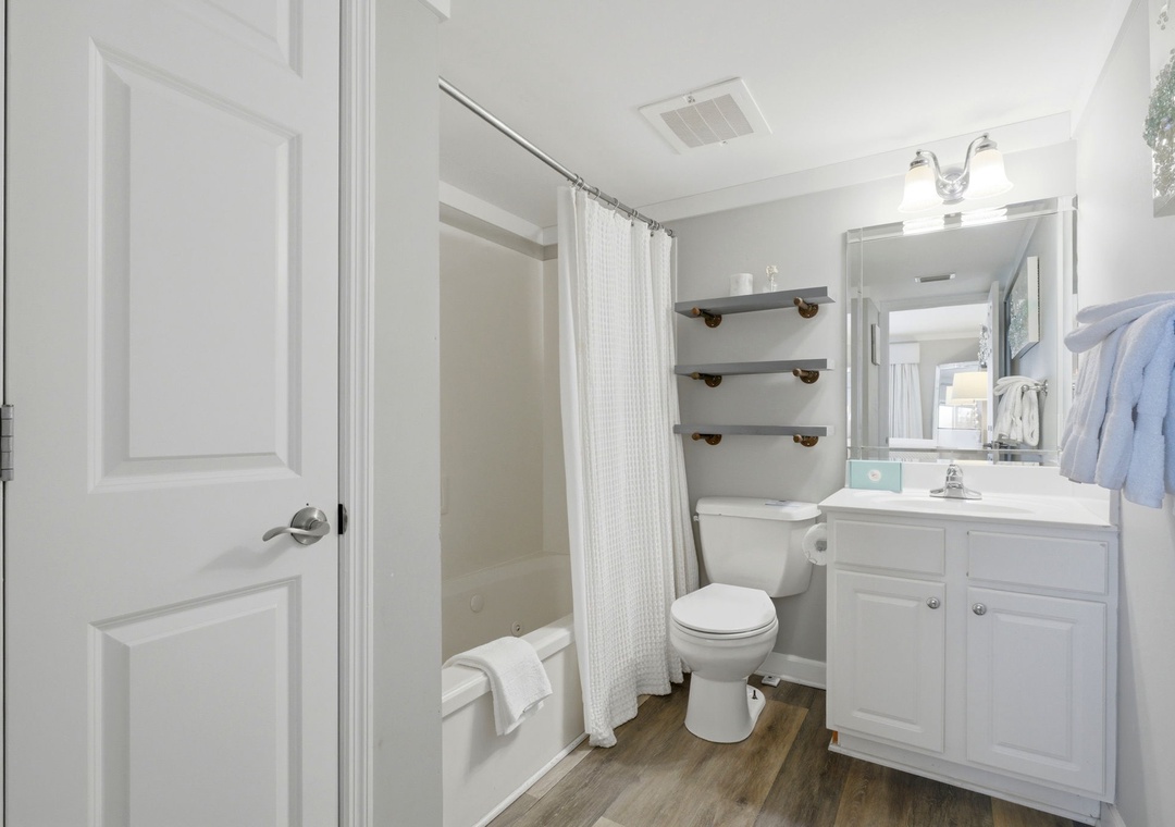 Sandy Key 827- Step into your bright, private bathroom with fresh white linens, open shelving for your essentials, and a modern tub-shower combo to refresh after a day of exploring.