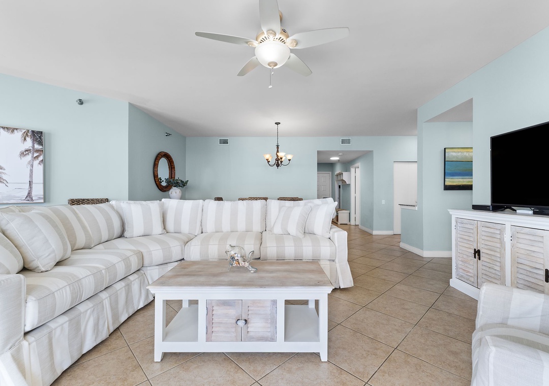 Beach Colony Tower 10C- Picture yourself settling into this bright coastal living space, where soft striped seating and calming aqua walls create a serene retreat.