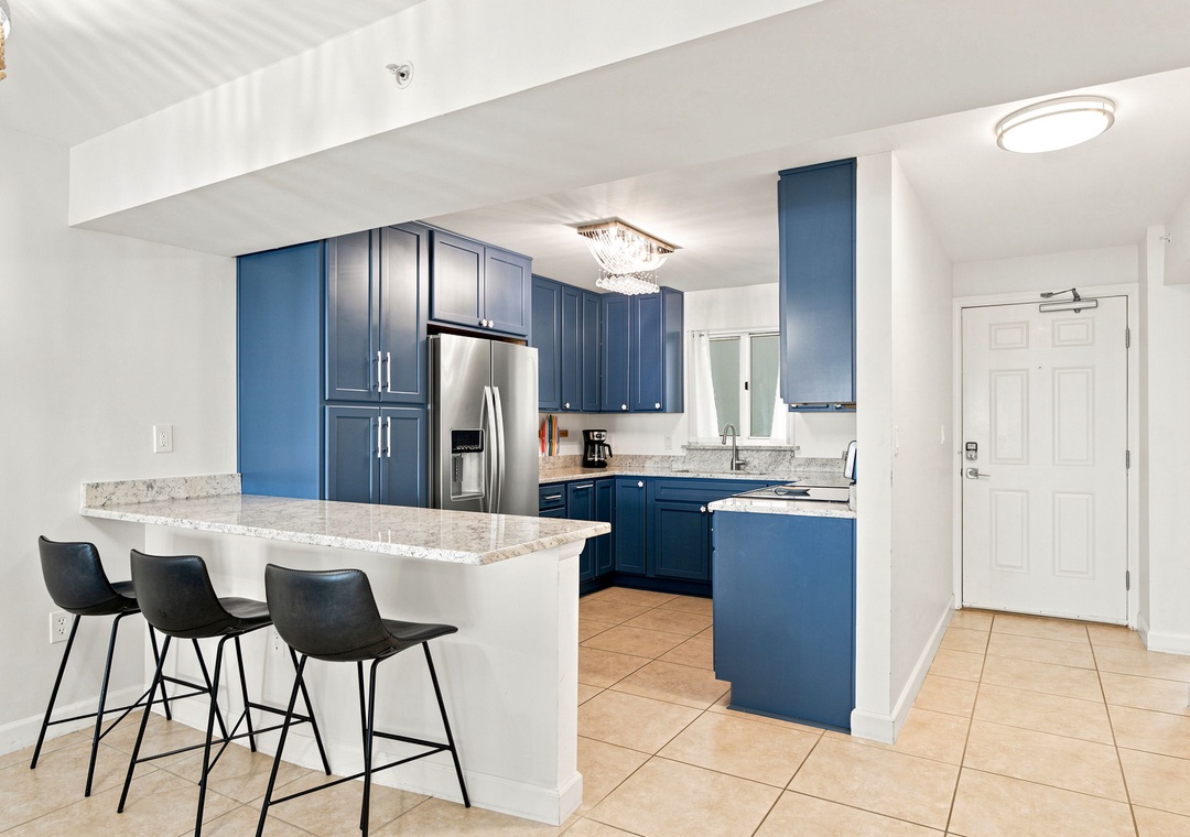 Sandy Key 411- Sleek blue cabinetry and natural light create an elegant, inviting kitchen. Three modern bar stools perfect for casual gatherings and morning coffee moments.