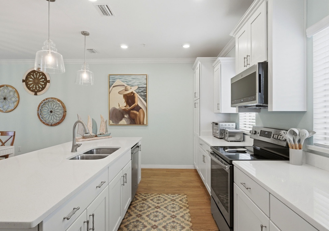 Step into your coastal-inspired kitchen where crisp white cabinetry meets nautical charm. You'll love preparing meals on gleaming countertops under soft pendant lighting, surrounded by beachy décor that brings vacation vibes home.
