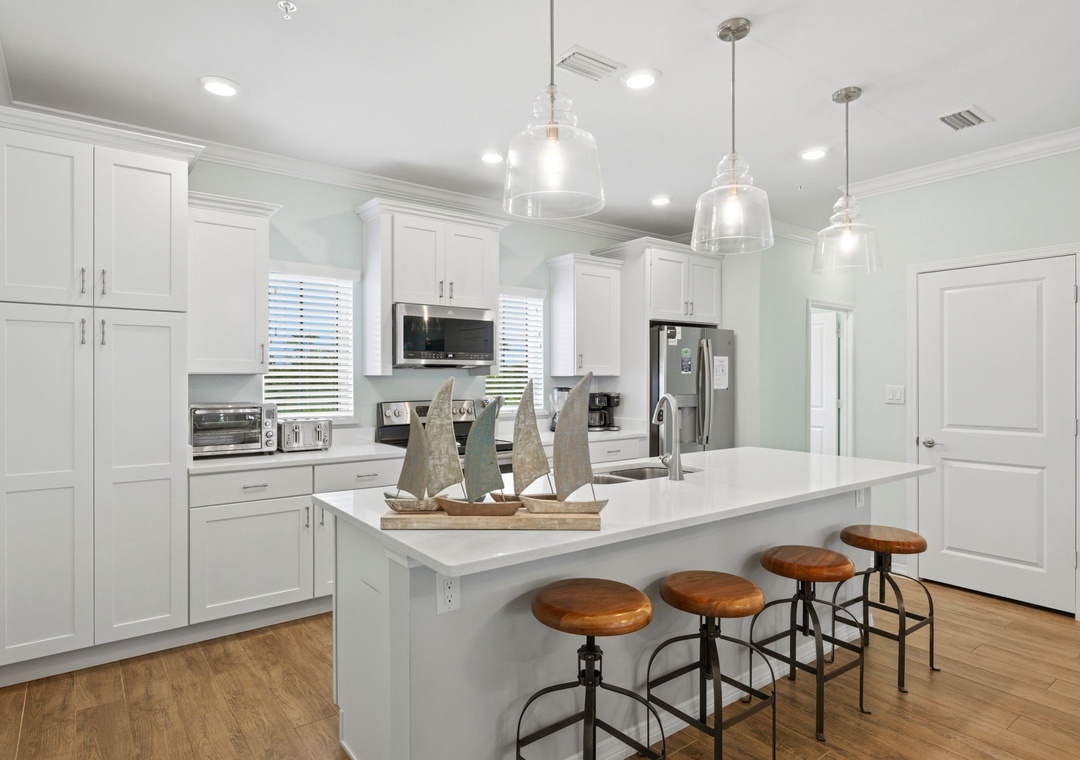 Your vacation kitchen is bright, spacious, and fully equipped with modern appliances, perfect for preparing meals with family. The large island invites you to gather over coffee or casual conversation.