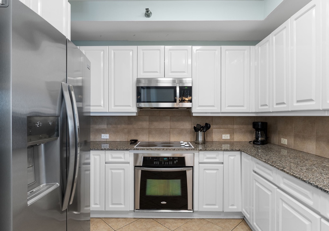 Beach Colony Tower 10C- Your fully equipped kitchen has everything you need: stainless steel appliances, granite countertops, crisp white cabinets, and space to prepare your favorite meals in comfort.