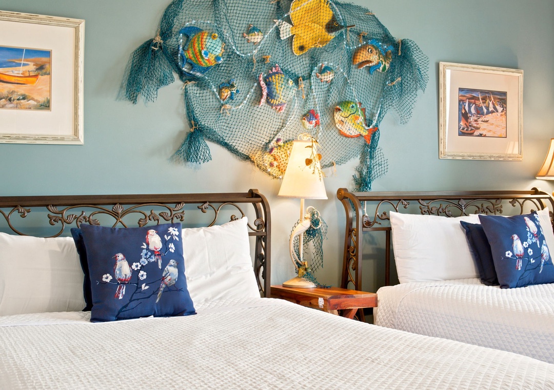 Beach Colony W13A- Two cozy beds with crisp white linens and nautical accents create your peaceful coastal retreat. Whimsical sea-life art and beachy charm set the tone for relaxation.
