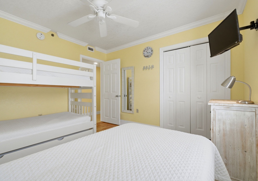 Ocean Breeze E601- Your cheerful room features a queen bed, bunk beds for the kids, wall-mounted TV, and a ceiling fan to keep you comfortable. Perfect for families seeking a cozy retreat.