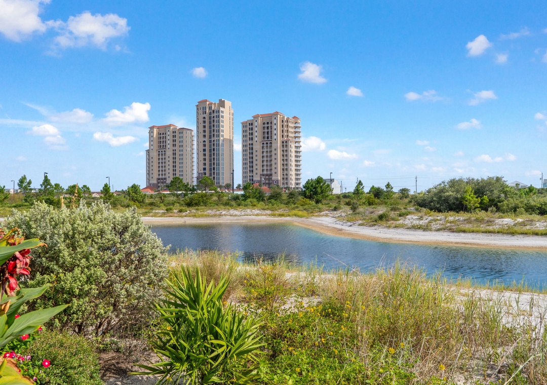 Saltwater & Sunsets- Property buildings situated in a scenic area with a natural pond, surrounded by lush greenery and blue skies.