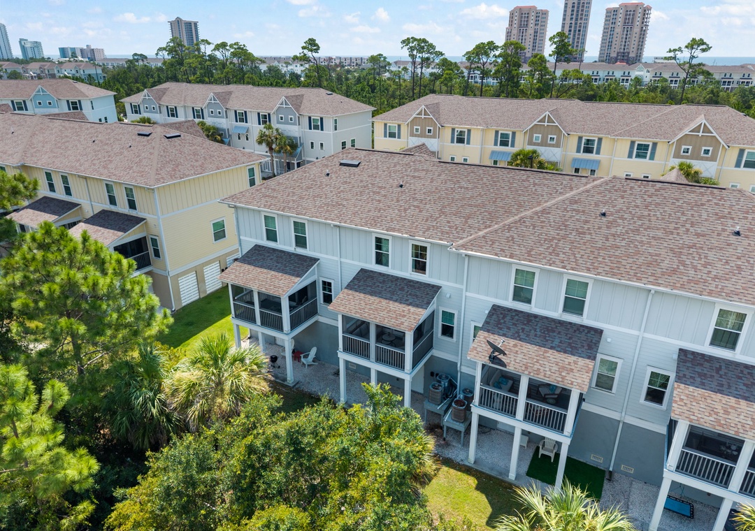 Turtles Nest- Aerial view of a coastal neighborhood with residential buildings surrounded by lush greenery and palm trees, featuring nearby high-rise towers and glimpses of the ocean in the distance.