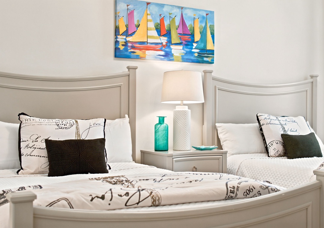 Two cozy beds dressed in crisp white linens with coastal accents invite you to unwind. Nautical artwork and soothing seaside tones make this your perfect beachside retreat.