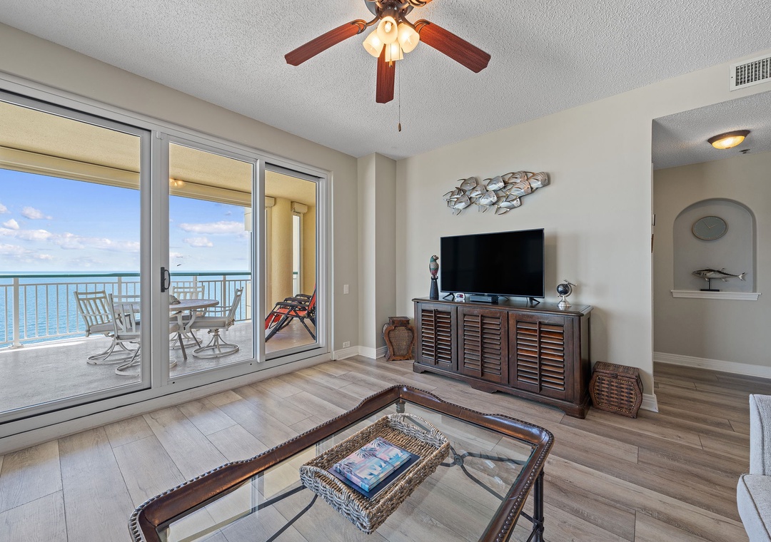 Beach Colony T15B- Step into your airy living space where floor-to-ceiling glass doors frame stunning turquoise waters just beyond your private balcony. The gentle ocean breeze and soothing ceiling fan create your perfect coastal retreat.