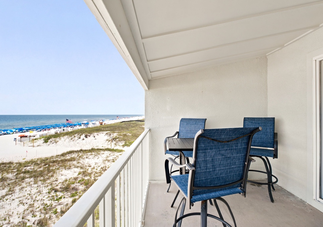 Gulfside Villas 2B- Beachfront balcony overlooking the Gulf, featuring dining seating with stunning white sand and turquoise water views. This rental is located directly on the shore, with beach access as part of the surrounding property area.