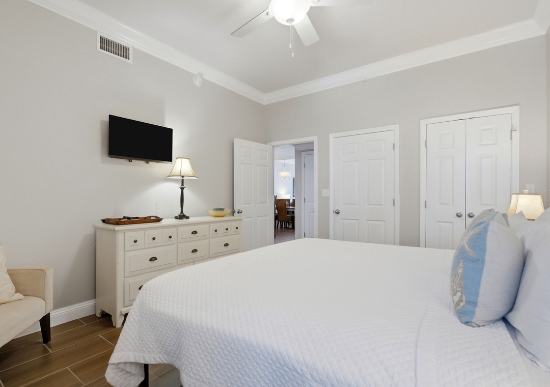 Your peaceful retreat features a plush bed, ceiling fan for comfort, entertainment on the wall-mounted TV, and plenty of storage. Soft lighting creates a serene atmosphere to unwind after a day of exploring.