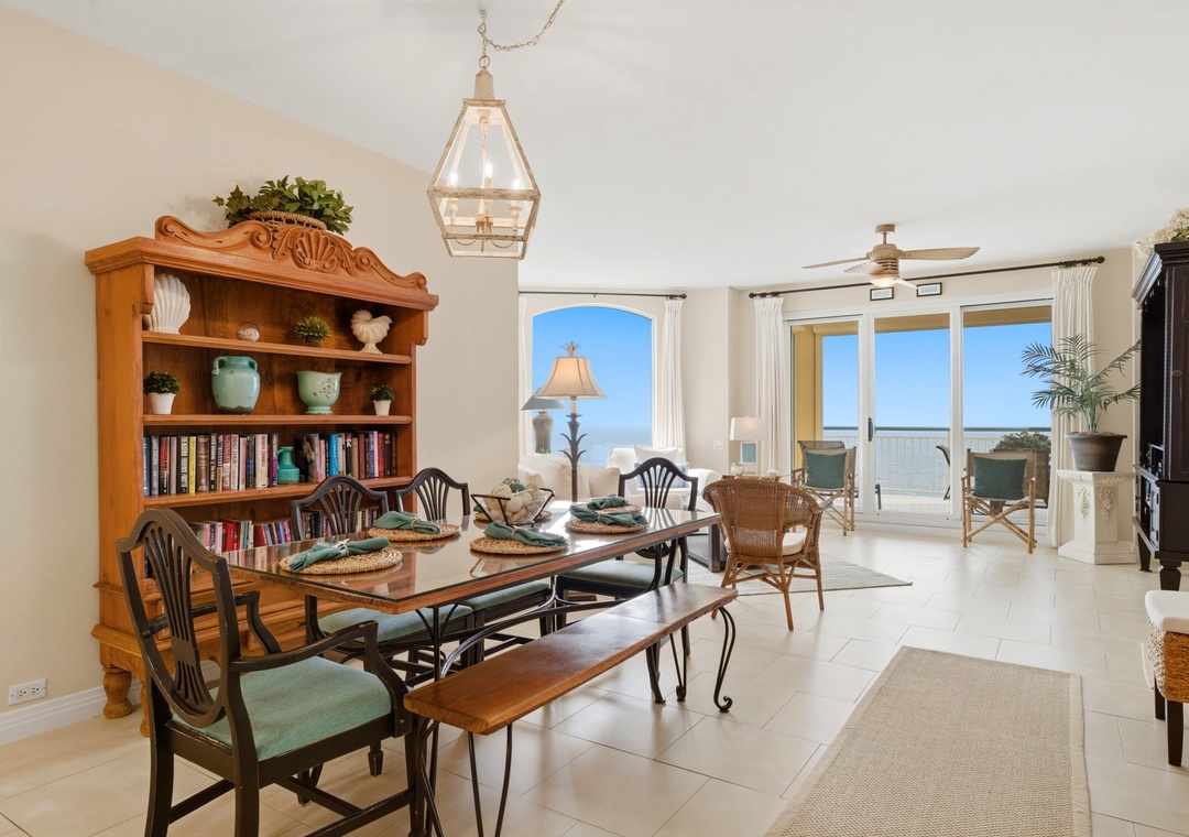 Beach Colony Tower PH1B - Your dining area opens to a sunlit balcony with sweeping ocean views, blending coastal charm with thoughtful touches like a cozy bookshelf and inviting table set for memorable meals together.