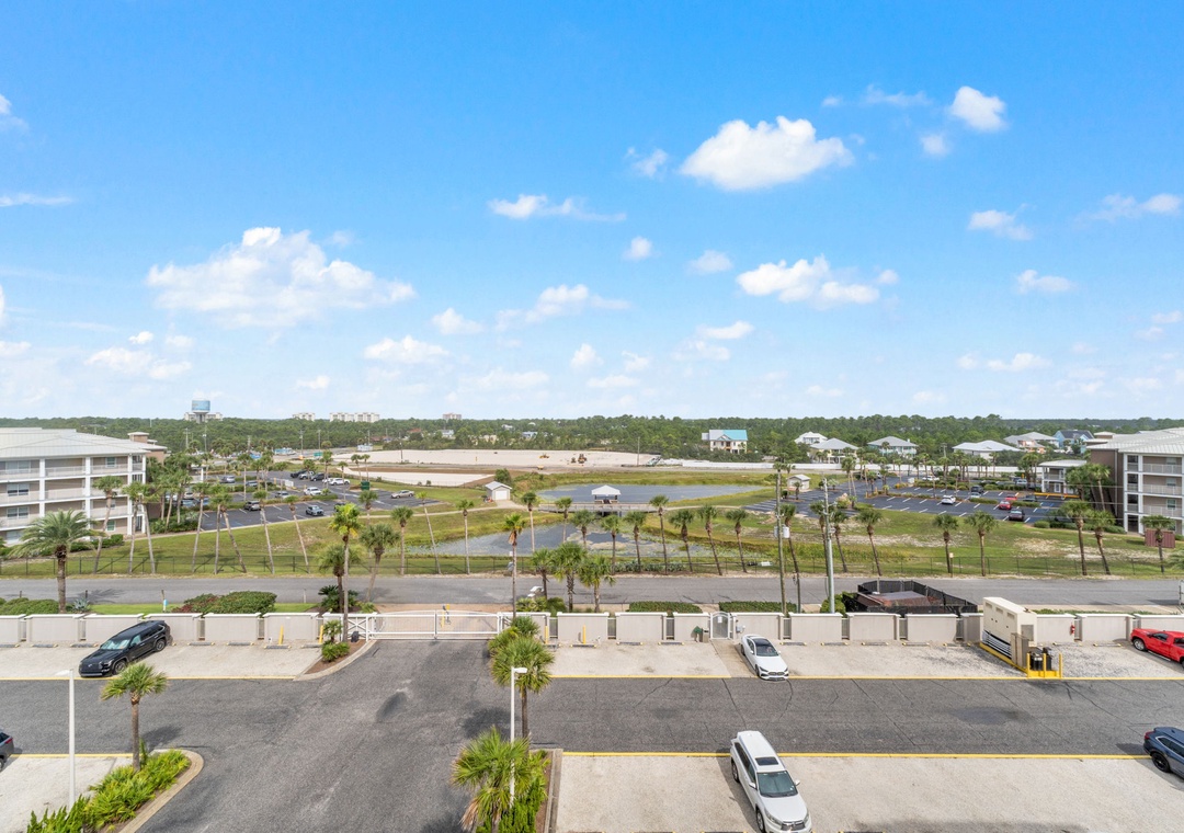 Sandy Key 628- A daytime aerial view captures the property's setting in a resort community, surrounded by palm-lined streets, landscaped grounds, and neighboring buildings visible across the open area.