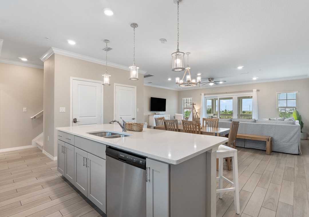 Saltwater & Sunsets- Modern open-concept living space with seamless kitchen, dining, and lounge areas. Natural light floods through large windows, complemented by elegant pendant lighting and sleek finishes.