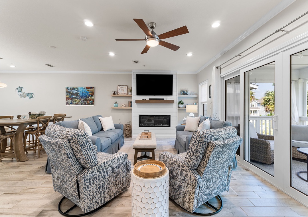 Turtles Nest- Settle into this bright, open living space where coastal blue seating faces a cozy fireplace. Natural light streams through sliding doors to the balcony, while the dining area and modern kitchen await your arrival.