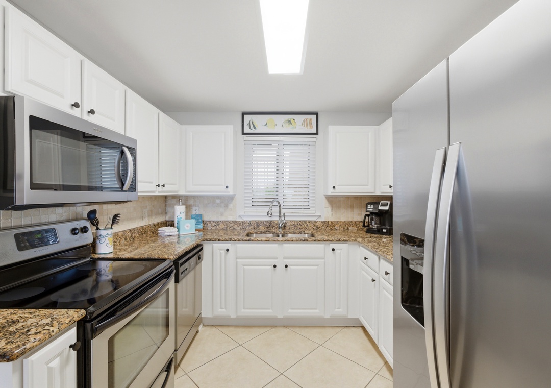 Sandy Key 318- Your fully equipped kitchen features crisp white cabinetry, granite countertops, and stainless steel appliances ready for your vacation meals.