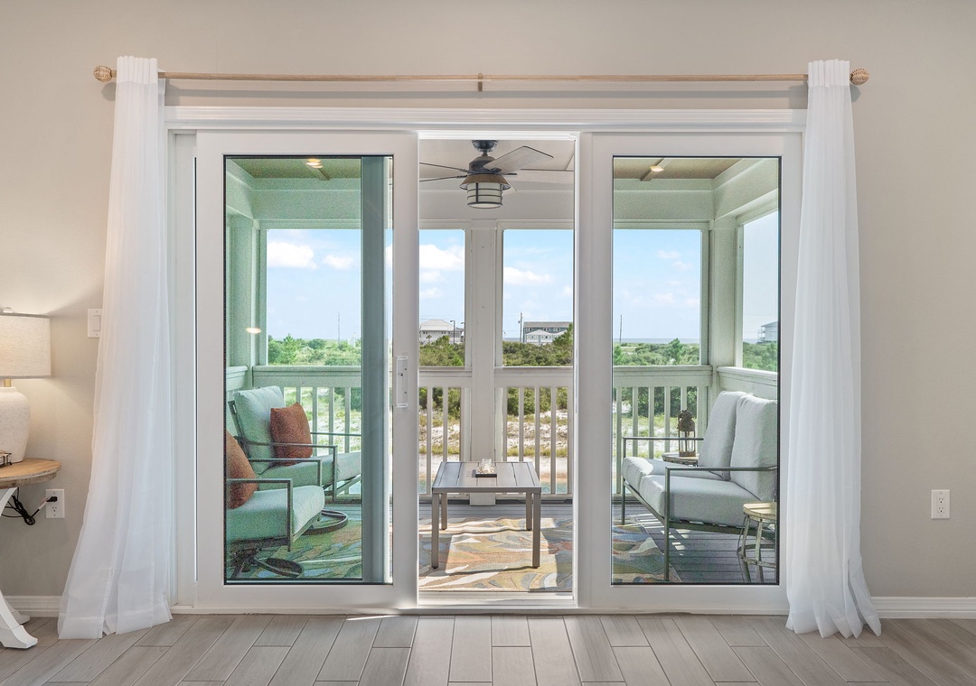 Saltwater & Sunsets- Step through to your private balcony where a cozy seating area awaits with calming views of the salt marshes and distant coastal scenery beyond.