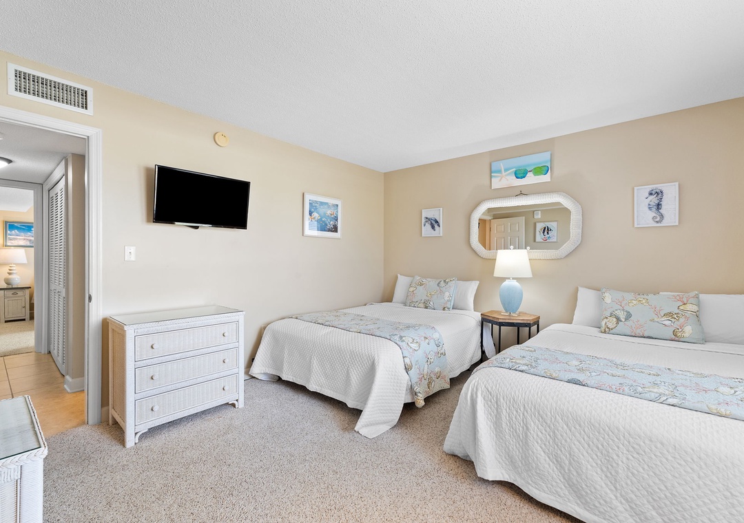 Sandy Key 628- Your coastal-inspired guest room features two plush beds dressed in soft linens, a bright TV for relaxation, and soothing beach-themed decor that invites you to unwind after sun-soaked days.