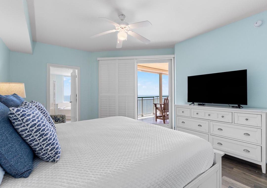Beach Colony Tower 10C- Step into your serene coastal bedroom, where calming blue walls and a plush bed create your personal retreat. Open the balcony doors to feel the Gulf breezes and enjoy sweeping views of the water from your private balcony