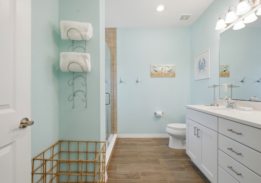 Your coastal-inspired bathroom awaits with crisp white cabinetry, soothing aqua walls, and charming nautical touches. Fresh towels and a spacious vanity make mornings effortless.