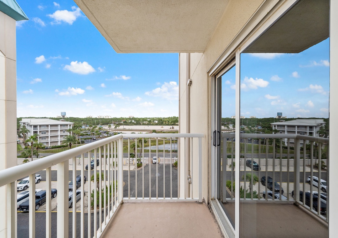 Sandy Key 628- Private balcony overlooking parking area and surrounding neighborhood buildings, offering open outdoor space with distant views and bright Florida skies.