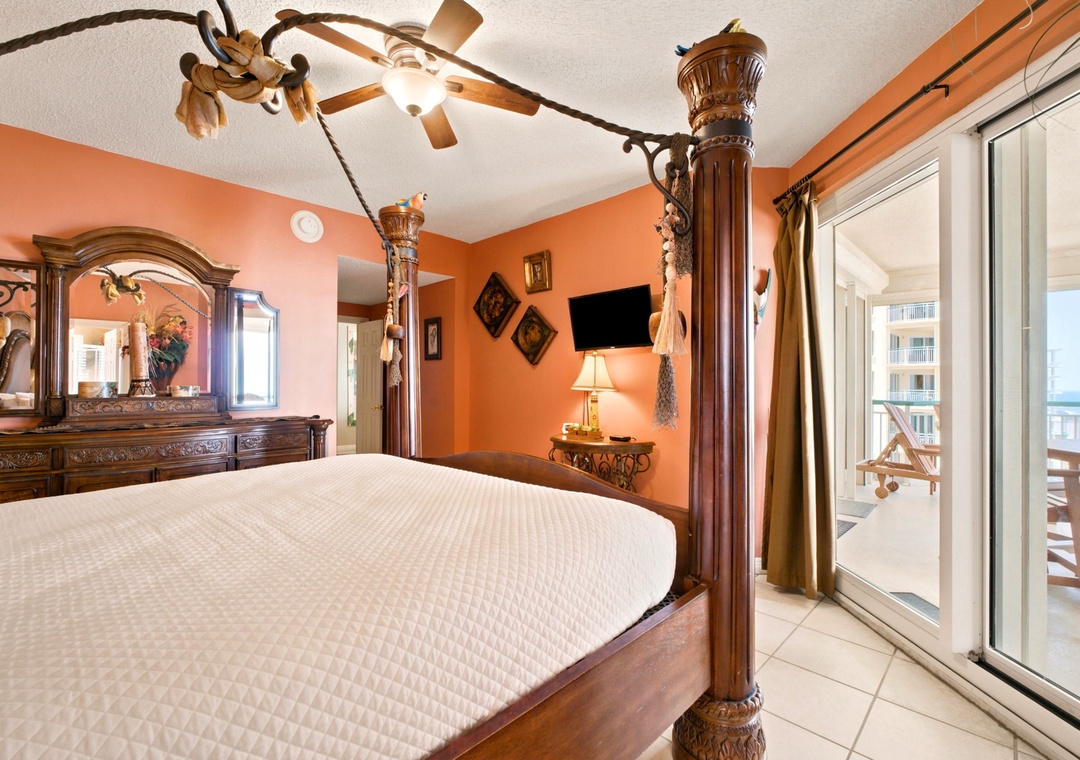 Beach Colony W13A- Step into your warm, elegantly furnished bedroom with a four-poster bed, ornate wooden furniture, and soothing coral walls. Your private balcony overlooks the sparkling sea—a perfect retreat.