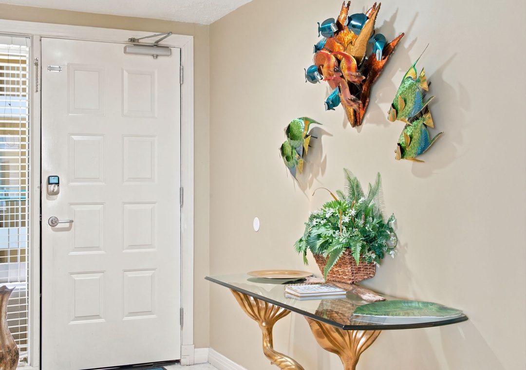Beach Colony W13A- A welcoming coastal entryway featuring vibrant tropical fish art and tropical greenery, setting a cheerful, beachy tone from the moment you arrive.